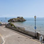 A view from a coastal road overlooking a sandy beach and St Catherine's Island in Tenby, Wales, near a Christian holiday flat.